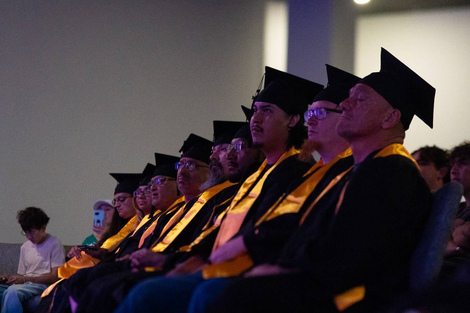 Residents seated in caps and gowns at an Under HIS Construction graduation ceremony